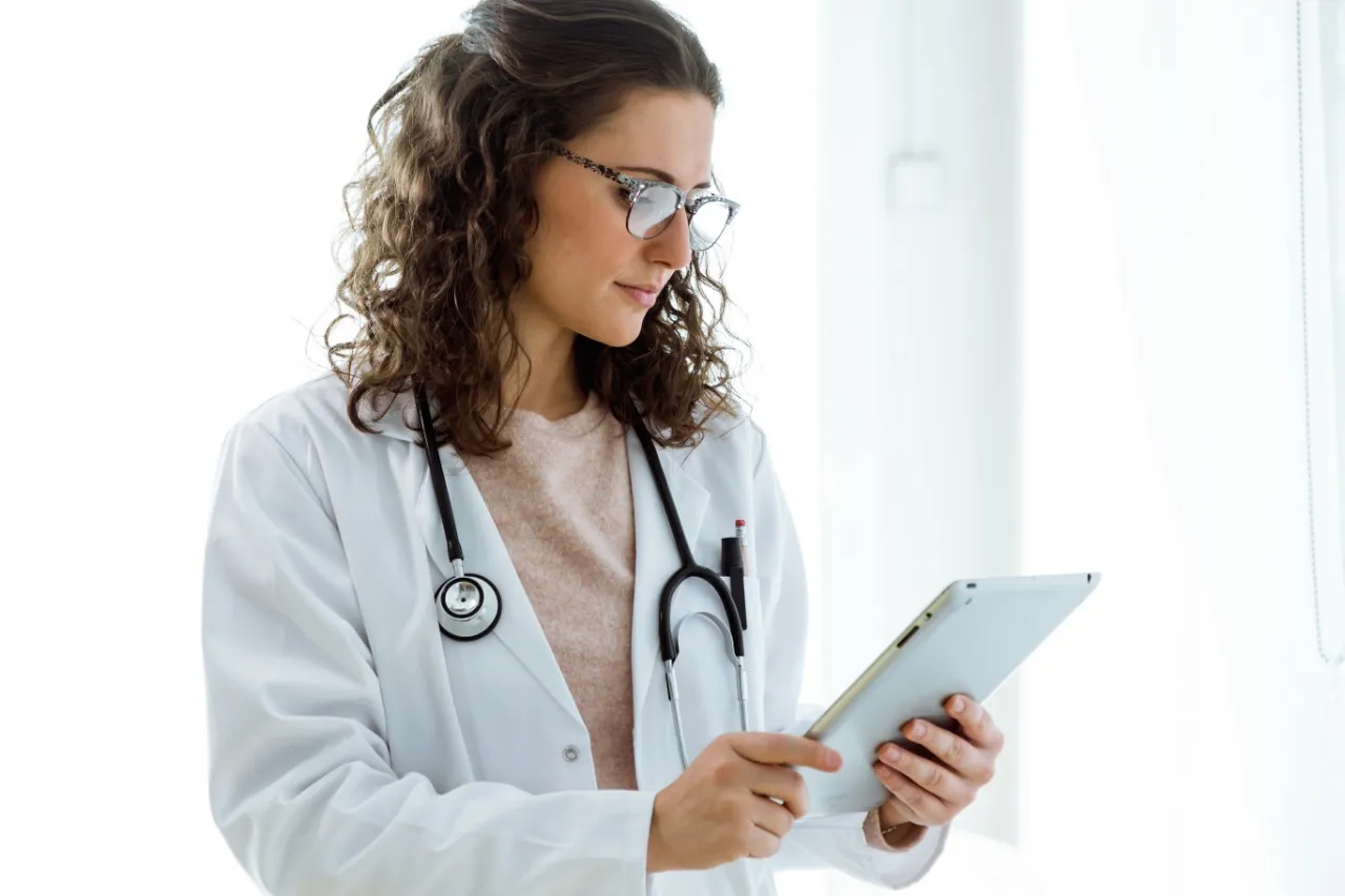 Médica con una tableta en la mano. Foto provisional de banco de imágenes.