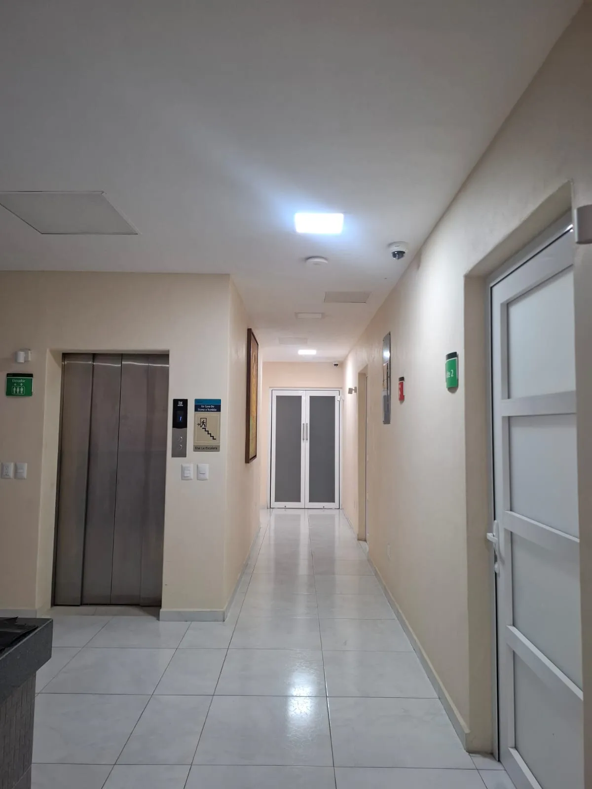 Pasillo con elevador, iluminación clara y puertas hacia las áreas de atención.