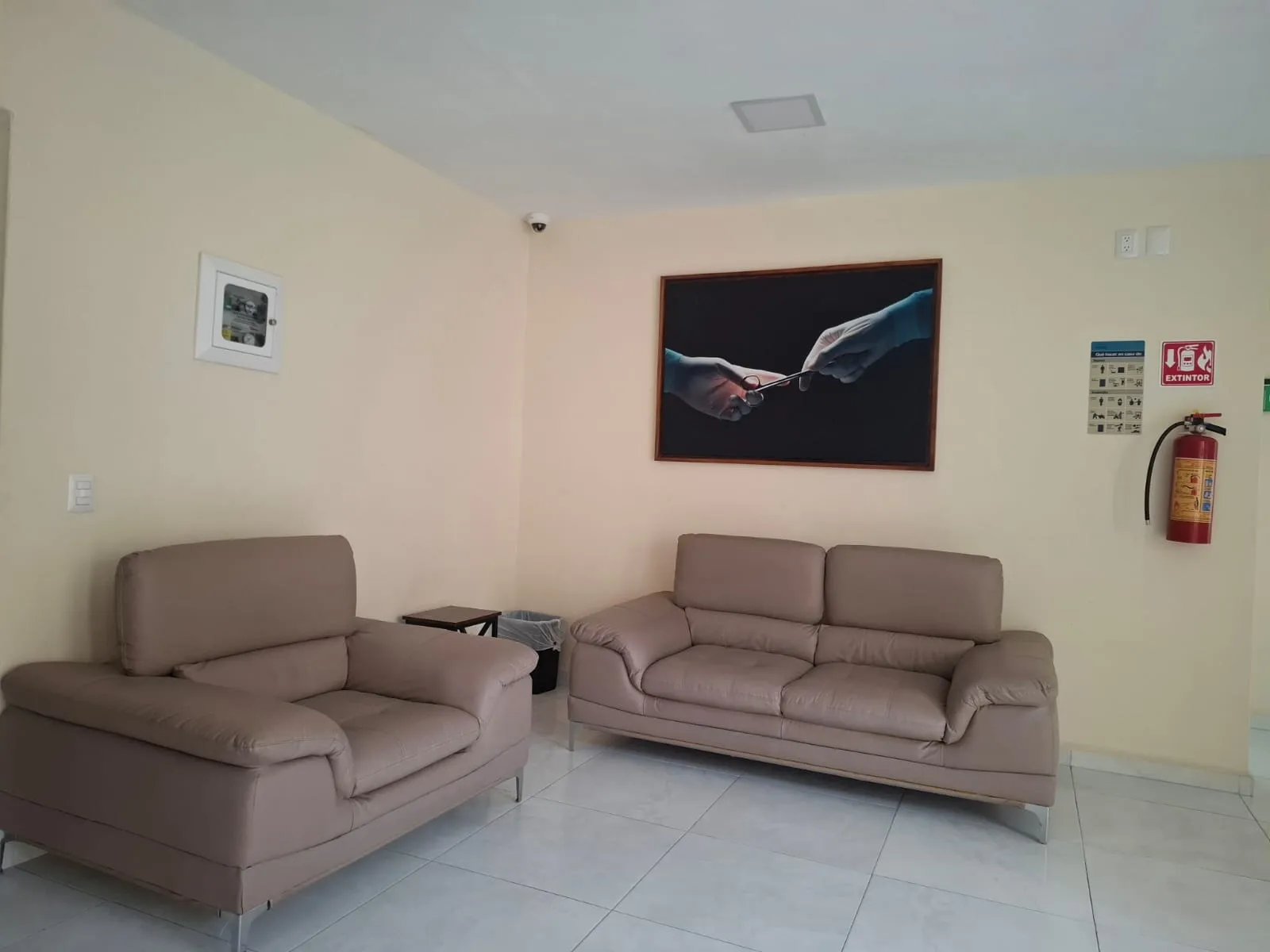 Sala de espera con sillones, cuadros y señalización de seguridad.